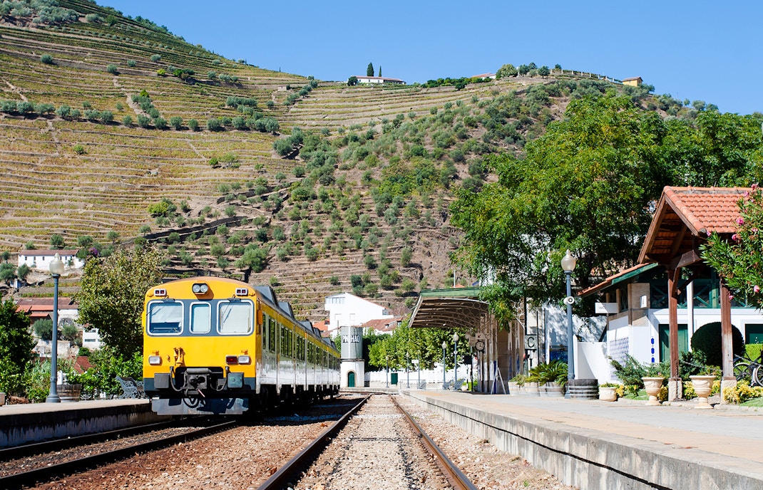 Train at Pinhão Railway Station with terraced vineyards in the background.