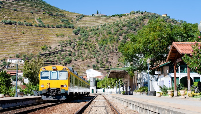 Train at Pinhão Railway Station with terraced vineyards in the background.