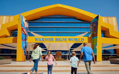 Family entering Warner Bros. World Abu Dhabi with Superman and Scooby-Doo murals.