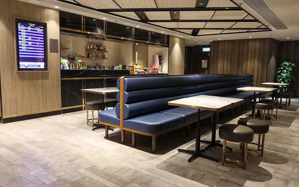 Plaza Premium Lounge seating area with bar and flight information display.