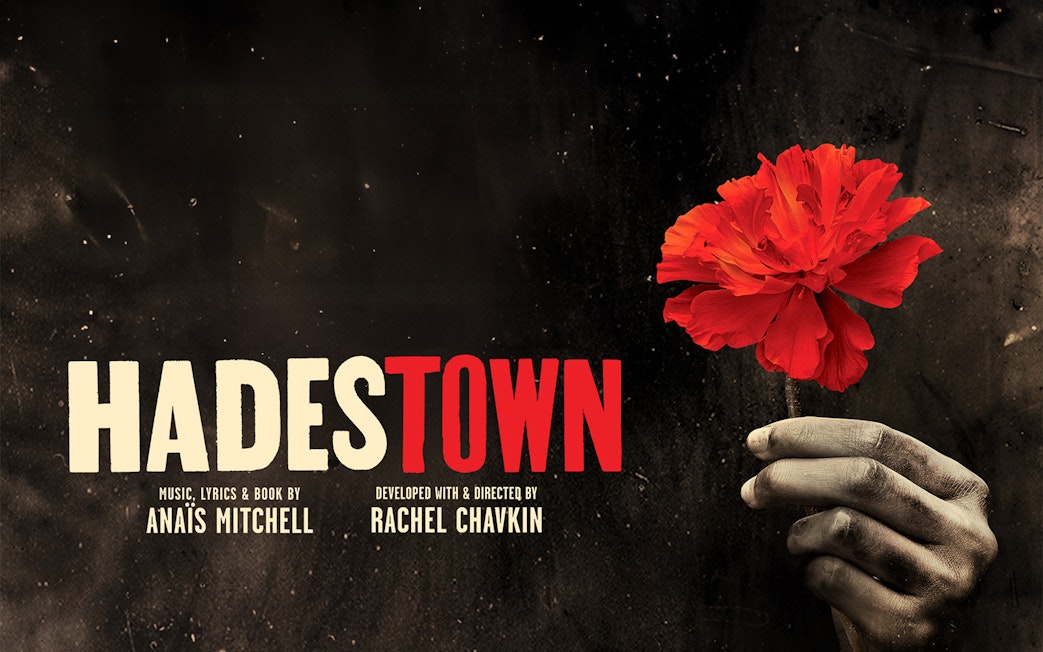 Hand holding a red flower with Hadestown text on a dark background.