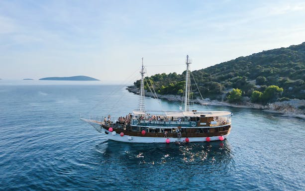 Boat party at Blue Lagoon near Split, Croatia with people swimming and enjoying the sea.