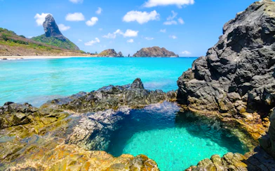 Crystal waters of Buraco do Galego natural pool with rocky coastline, Noronha, Sao Paulo.