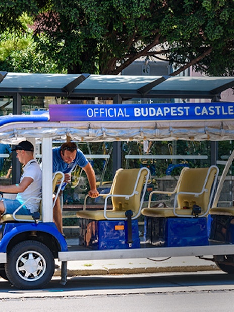 Official Budapest Castle bus parked at a stop with passengers boarding.