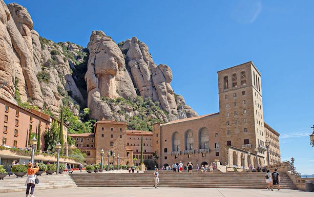 Montserrat Monastery with visitors and rocky mountain backdrop in Catalonia, Spain.