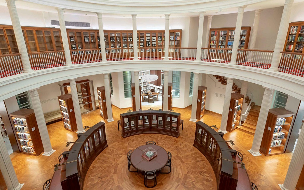 Library interior with bookshelves and reading table, National Gallery Singapore.