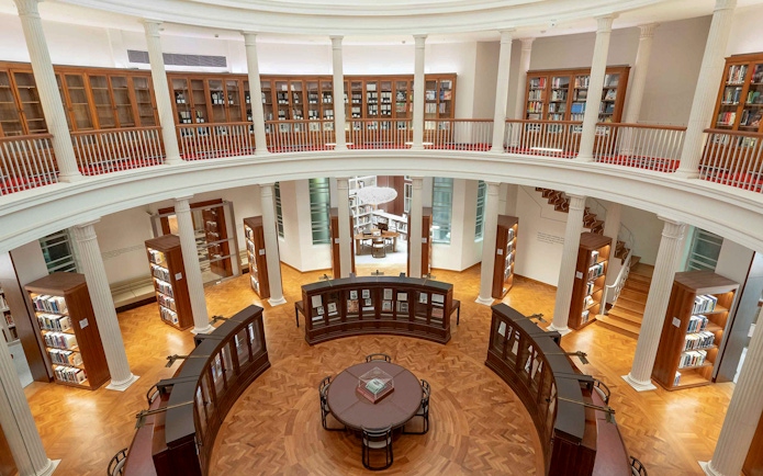 Library interior with bookshelves and reading table, National Gallery Singapore.
