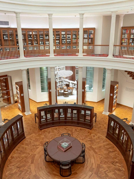 Library interior with bookshelves and reading table, National Gallery Singapore.