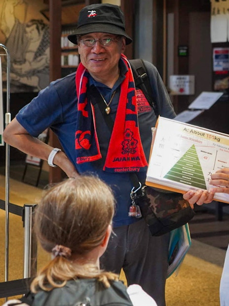 Guide explaining sumo wrestling details to tourists in Ryogoku, Tokyo.