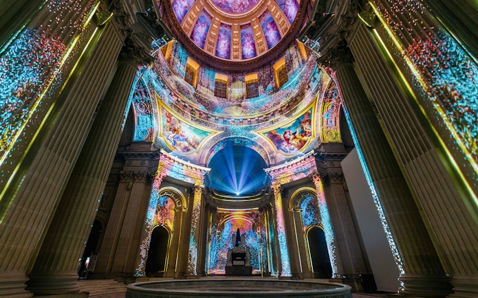 Immersive light display inside Invalides dome, Paris, showcasing vibrant projections.