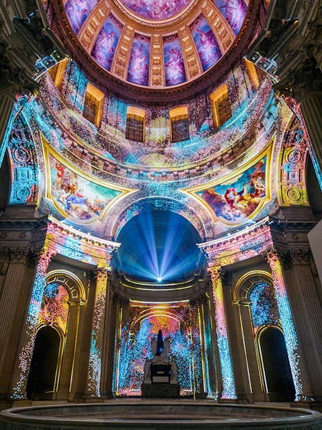 Immersive light display inside Invalides dome, Paris, showcasing vibrant projections.