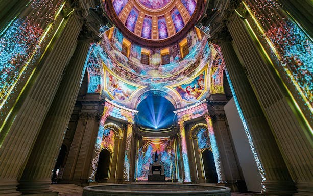 Immersive light display inside Invalides dome, Paris, showcasing vibrant projections.
