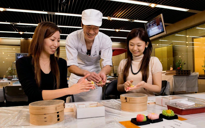 Cooking class with a chef teaching two women to make traditional Japanese sweets in Shirakawa-go.