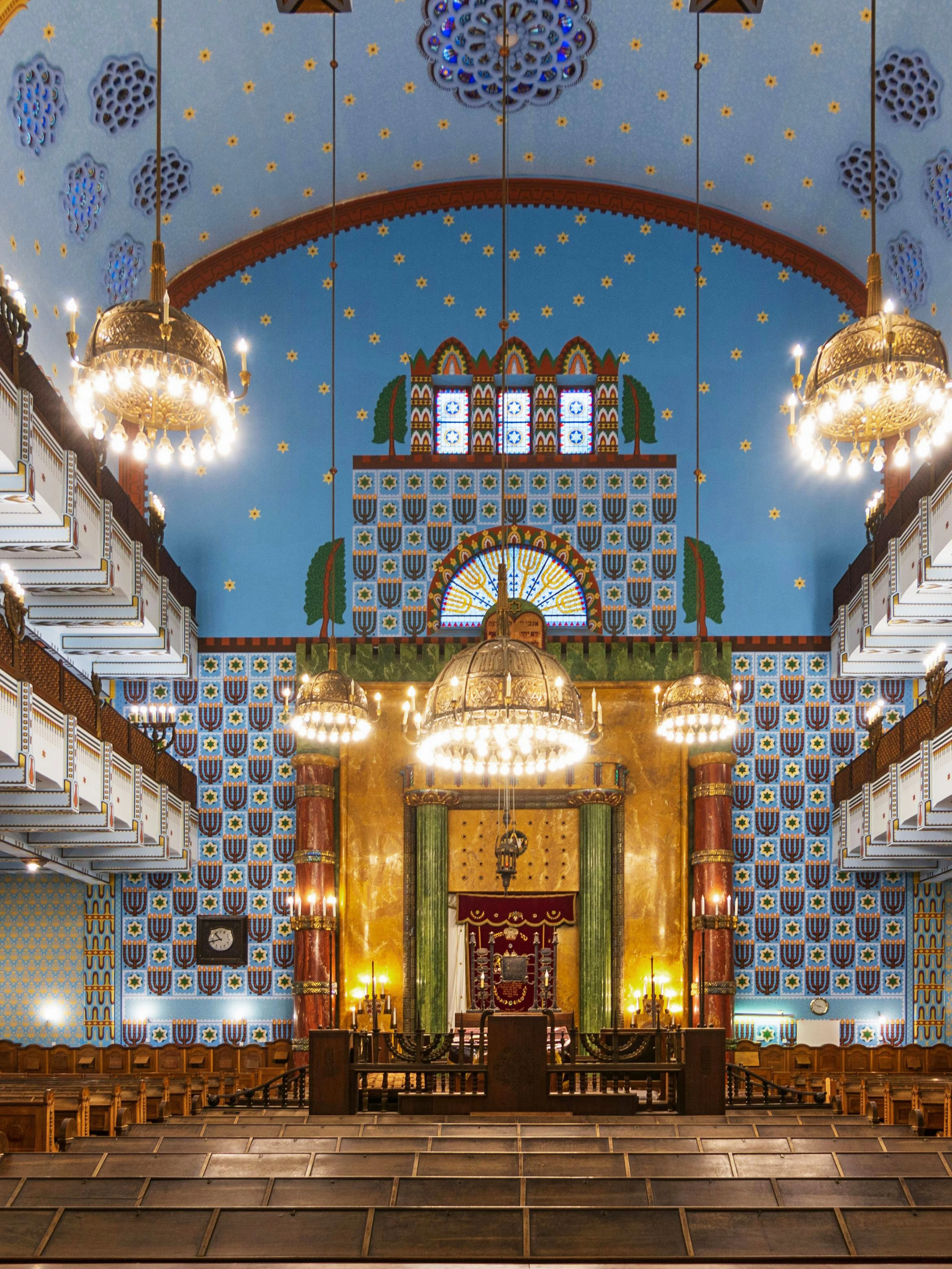 Kazinczy Street Synagogue interior with ornate chandeliers and colorful wall patterns, Budapest Jewish Quarter.