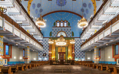 Kazinczy Street Synagogue interior with ornate chandeliers and colorful wall patterns, Budapest Jewish Quarter.
