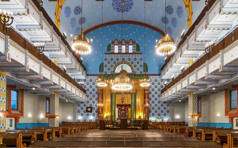 Kazinczy Street Synagogue interior with ornate chandeliers and colorful wall patterns, Budapest Jewish Quarter.