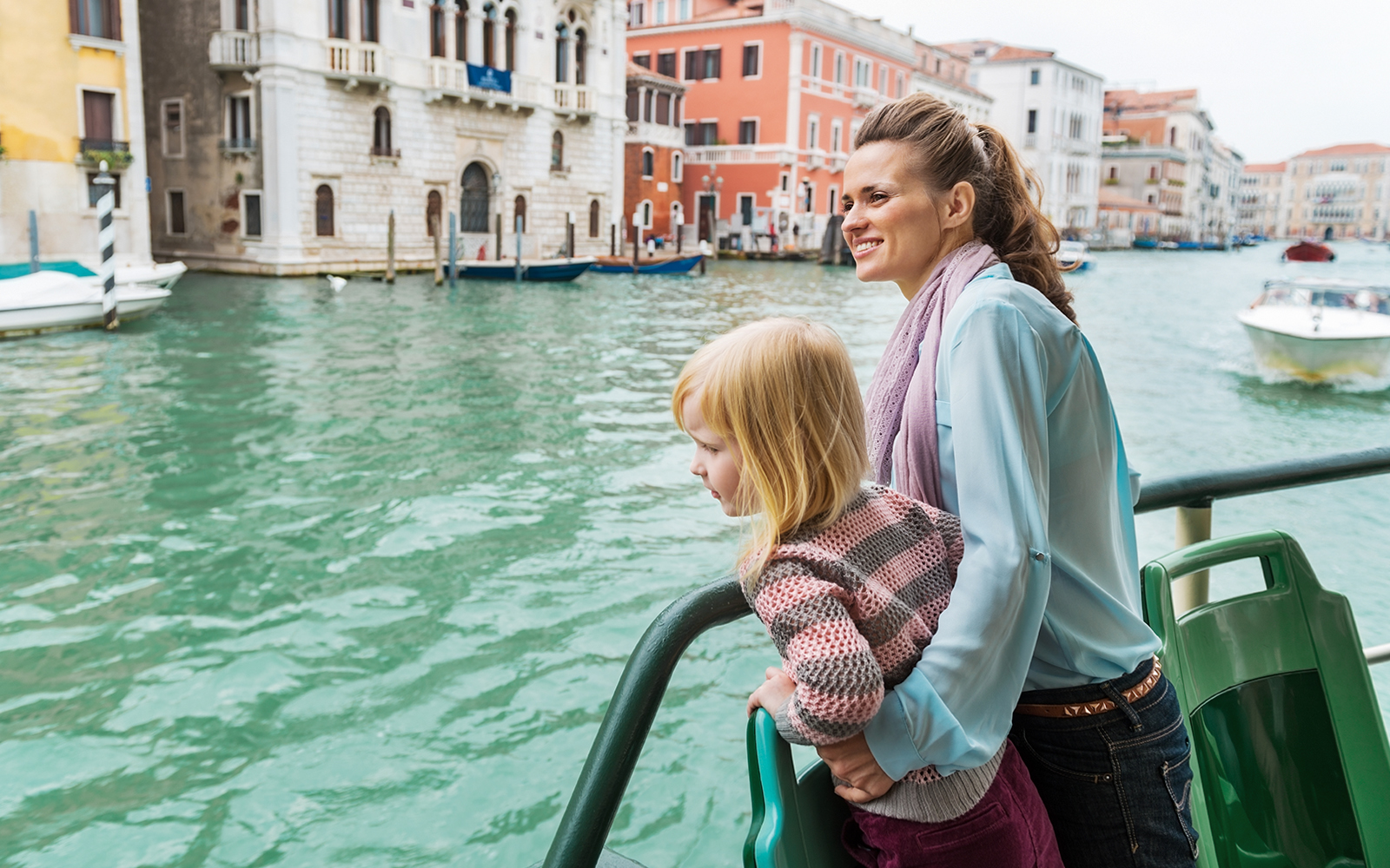 Mother and daughter on Venice water bus with cityscape in background