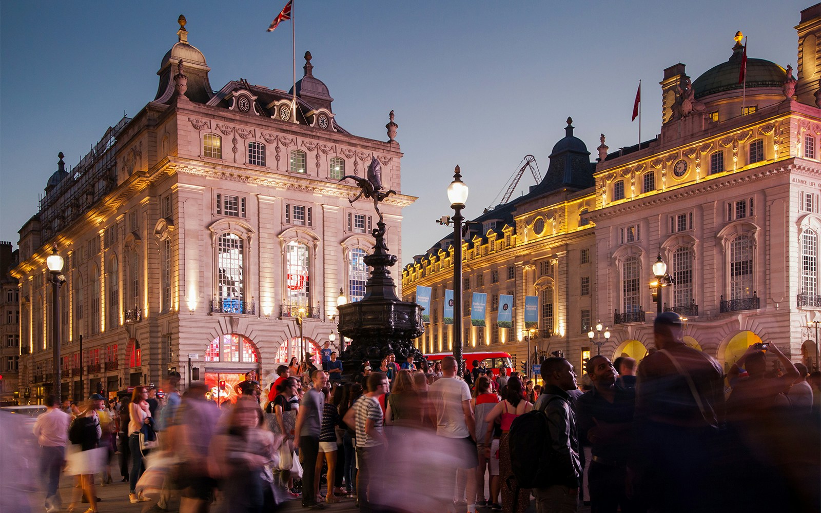 Crowd at Piccadilly Circus, London, with illuminated buildings and Eros statue at night.