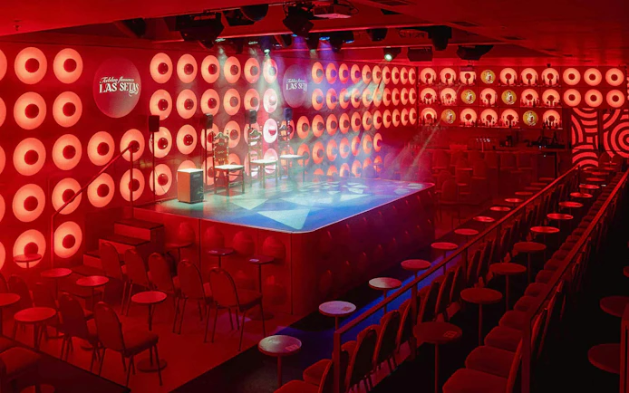 Las Setas stage area with red lighting and seating arrangement.