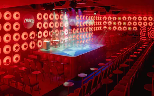 Las Setas stage area with red lighting and seating arrangement.