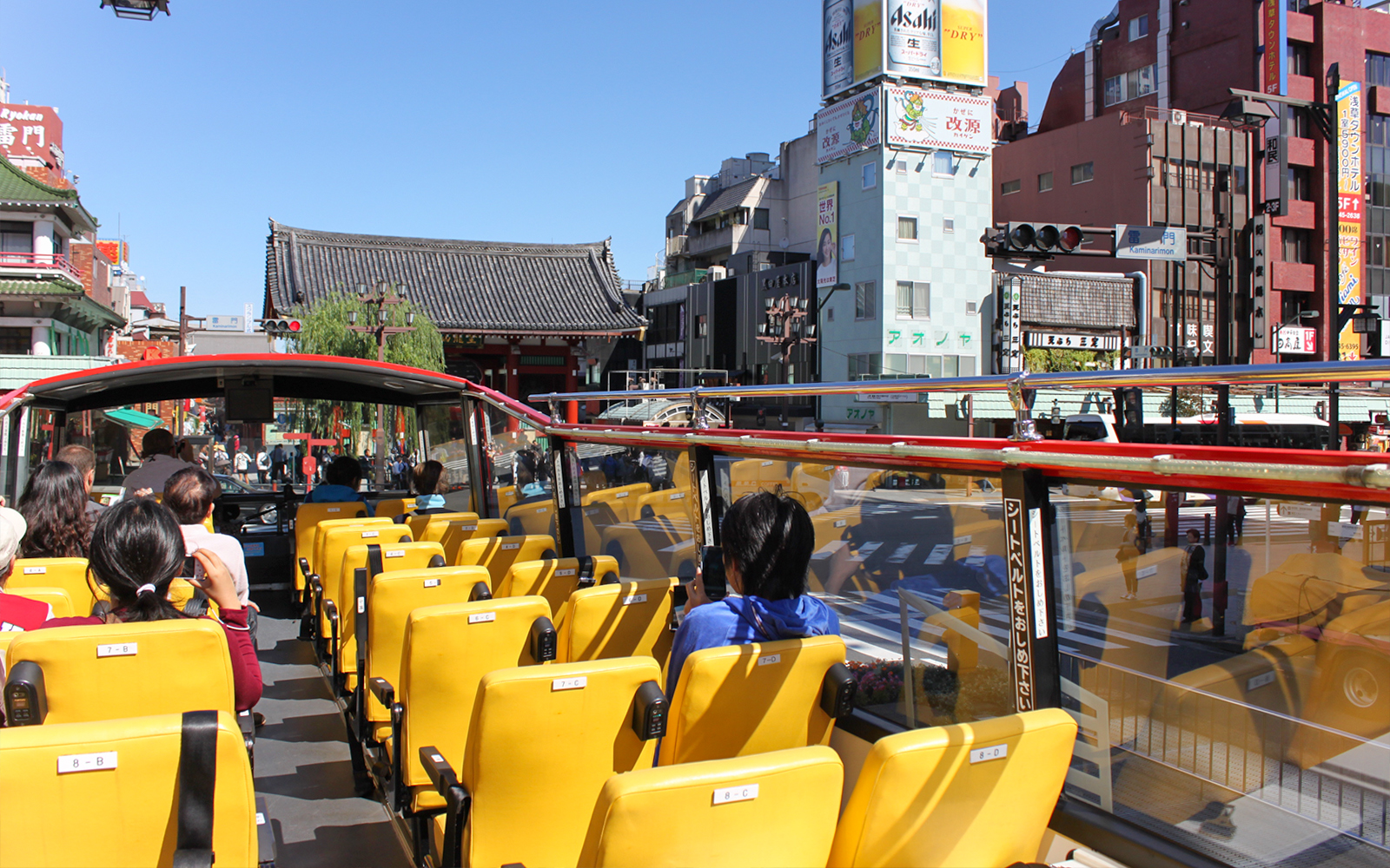 Tourists on Sky Hop bus passing through Asakusa, Tokyo with Senso-ji Temple in view.