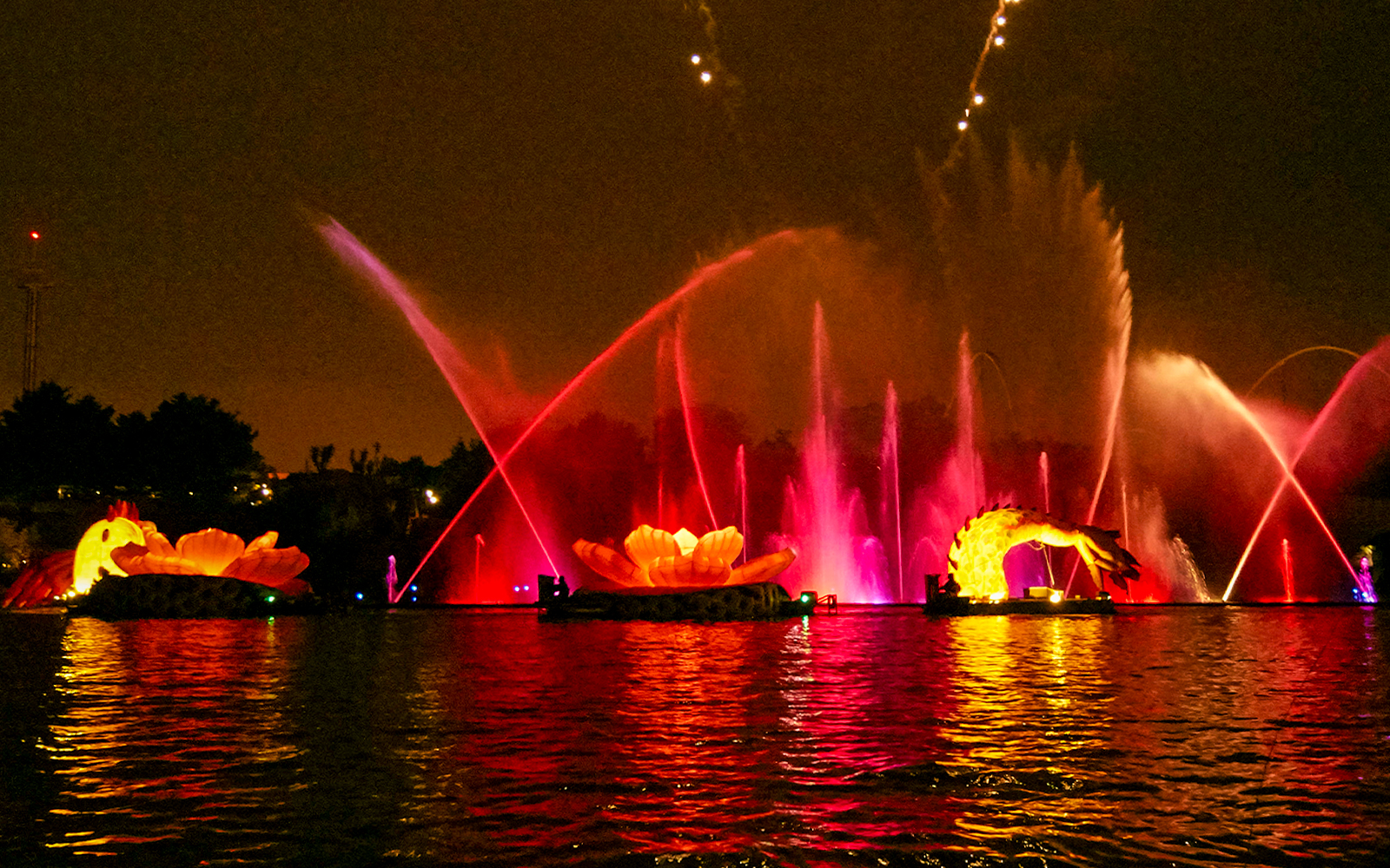 Port Aventura FiestAventura night show with vibrant fireworks over the illuminated lagoon in Spain.