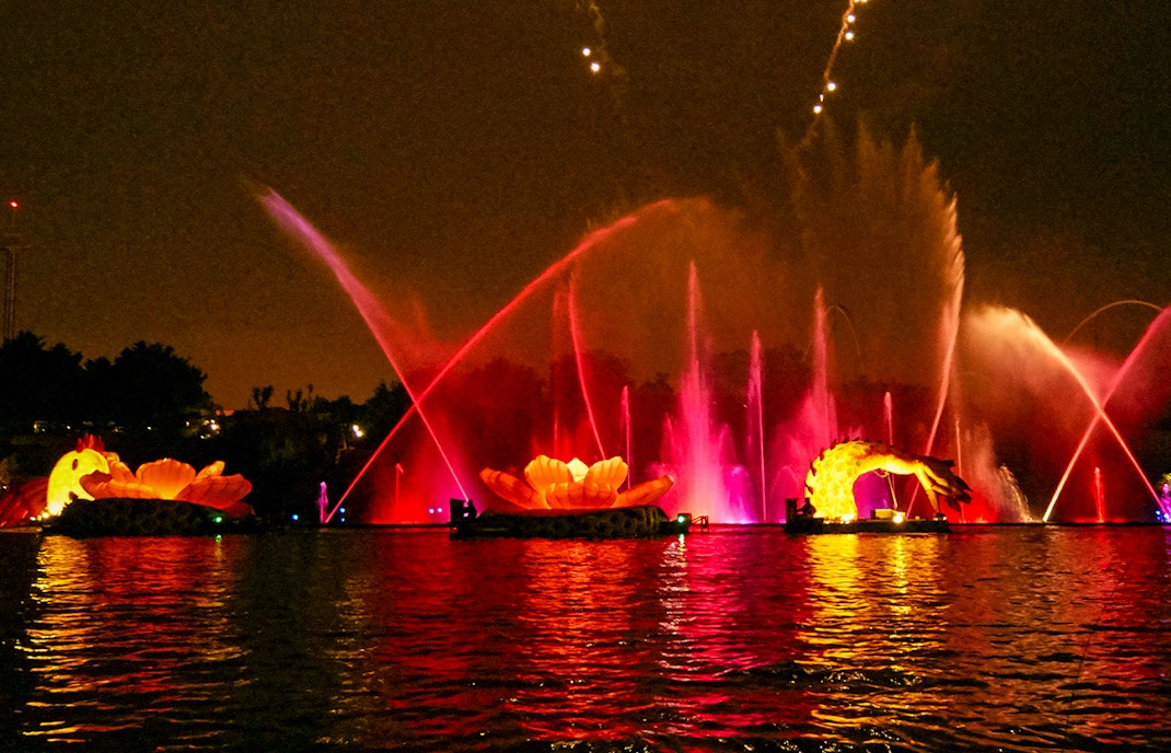 Port Aventura FiestAventura night show with vibrant fireworks over the illuminated lagoon in Spain.