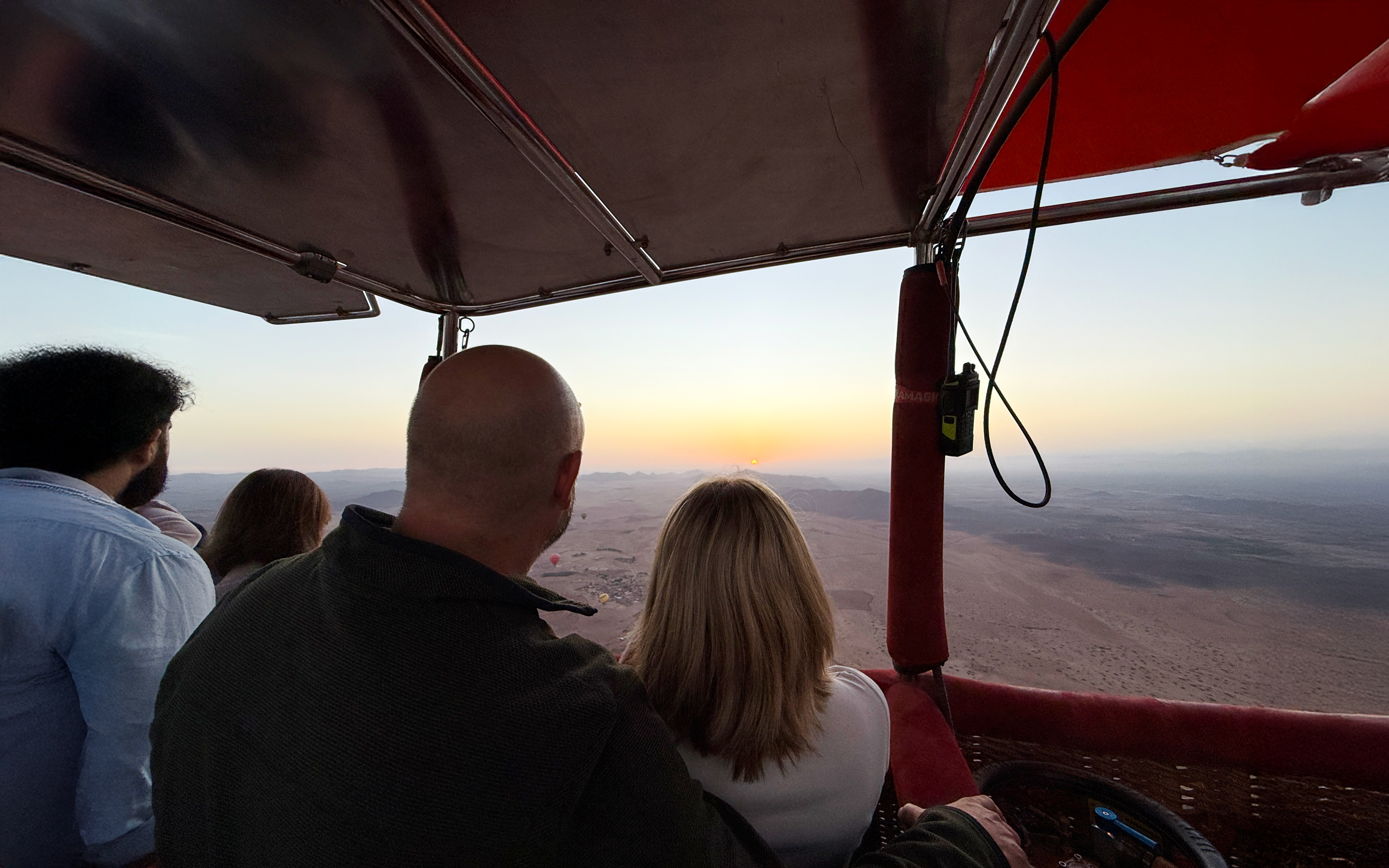 Couple enjoying sunrise view from hot air balloon over Marrakech desert.