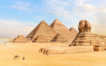 Pyramids of Giza and Sphinx in Egypt with a person leading a camel in the foreground.