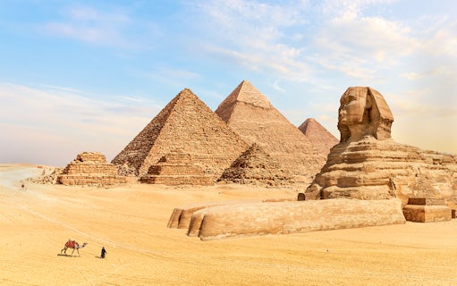 Pyramids of Giza and Sphinx in Egypt with a person leading a camel in the foreground.