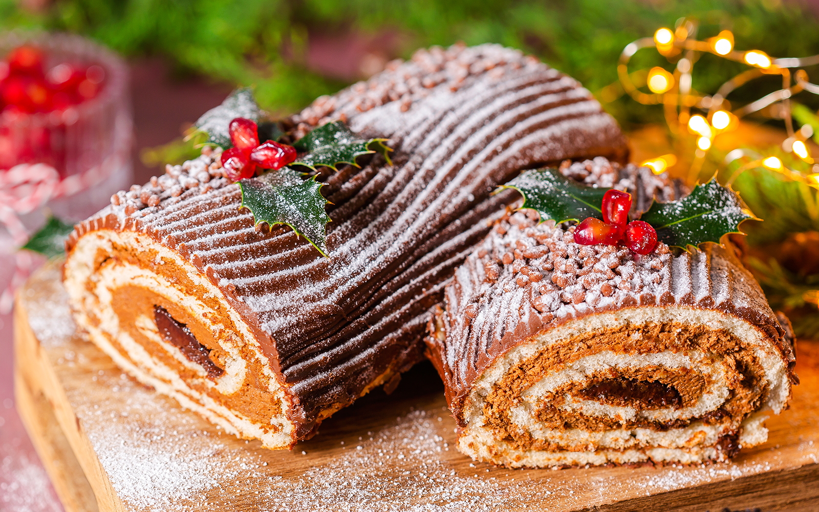 Christmas log cake with chocolate frosting, dusted with powdered sugar and decorated with holly.