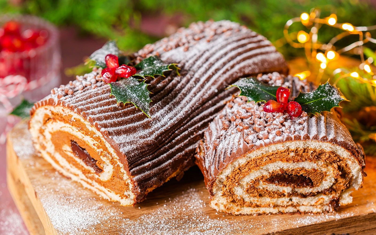 Christmas log cake with chocolate frosting, dusted with powdered sugar and decorated with holly.