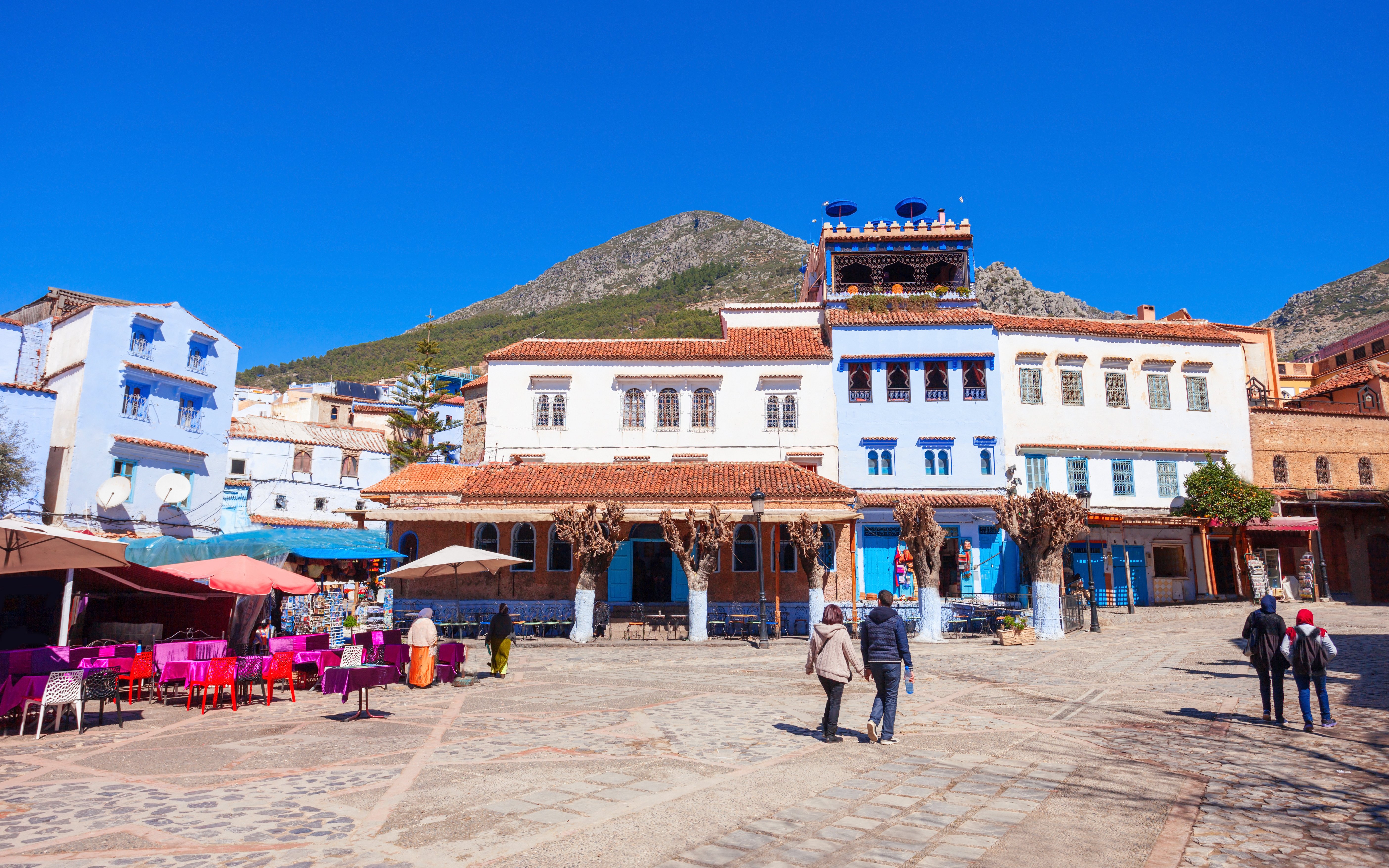 Tourists walking through the blue streets of Chefchaouen, Morocco.