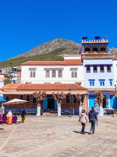 Tourists walking through the blue streets of Chefchaouen, Morocco.