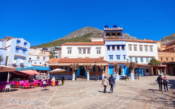Tourists walking through the blue streets of Chefchaouen, Morocco.