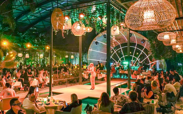 Performer on stage at Nouba Restaurant Dinner Show with audience dining.