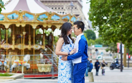 Couple embracing near carousel with Eiffel Tower in background, Paris.