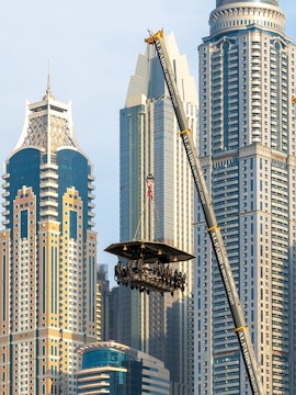 Dinner in the Sky experience suspended by crane with Dubai skyscrapers in the background.