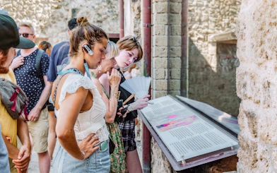 Visitors reading informational displays on a guided tour in Pompeii.