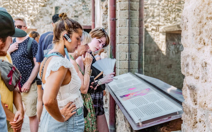 Visitors reading informational displays on a guided tour in Pompeii.