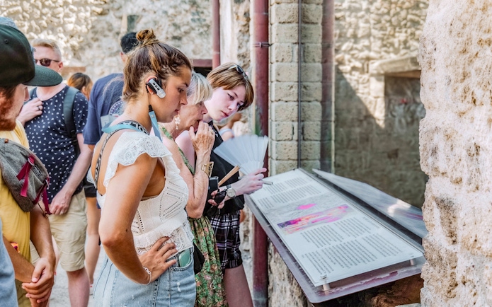 Visitors reading informational displays on a guided tour in Pompeii.