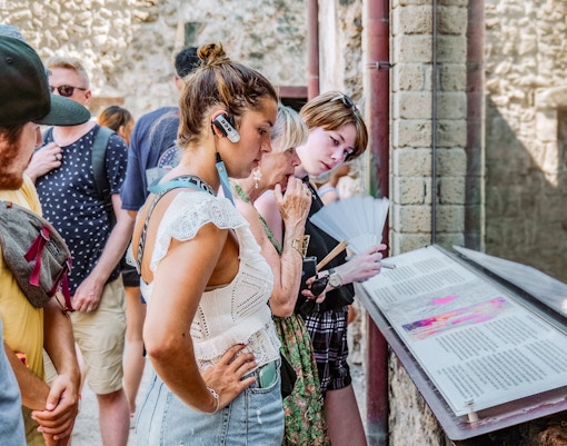 Visitors reading informational displays on a guided tour in Pompeii.