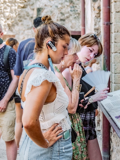 Visitors reading informational displays on a guided tour in Pompeii.