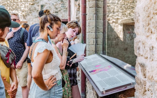 Visitors reading informational displays on a guided tour in Pompeii.