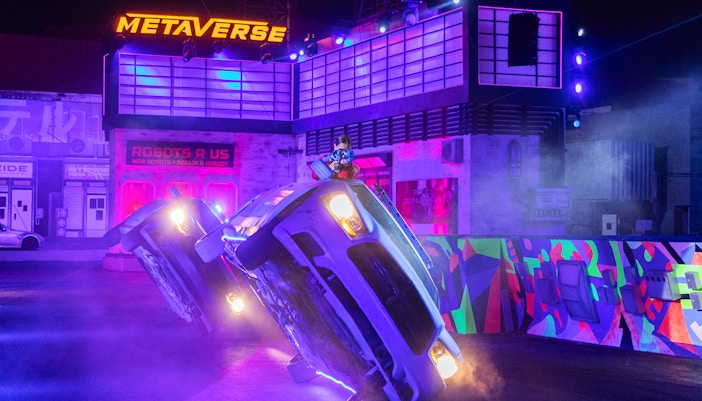 Car performing a stunt on two wheels at Global Village stunt show.