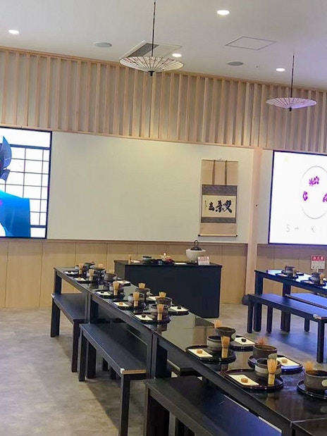 Matcha making class setup with tables, bowls, and whisks in a Japanese-style room.