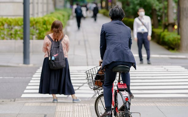 Cyclist on electric bike crossing street in Tokyo during city tour.
