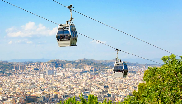 Montjuic Cable Car over Barcelona cityscape with distant hills.