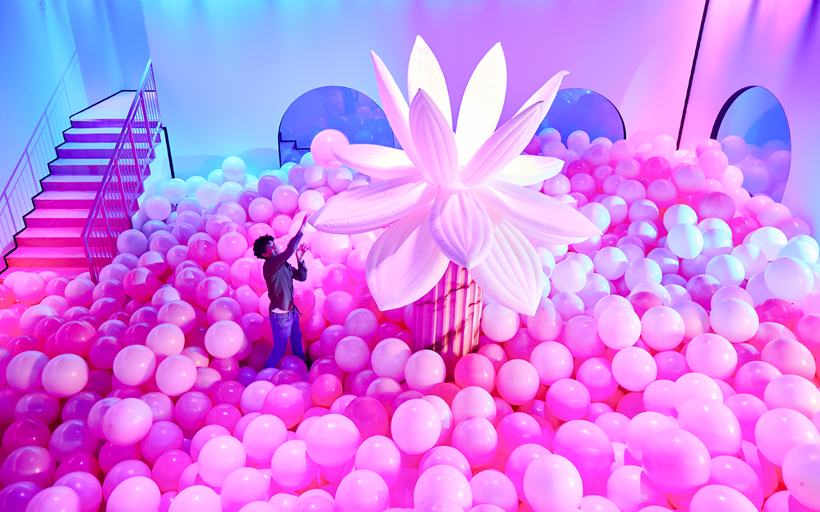 Person exploring pink balloon installation at Bubble Planet, Seattle.