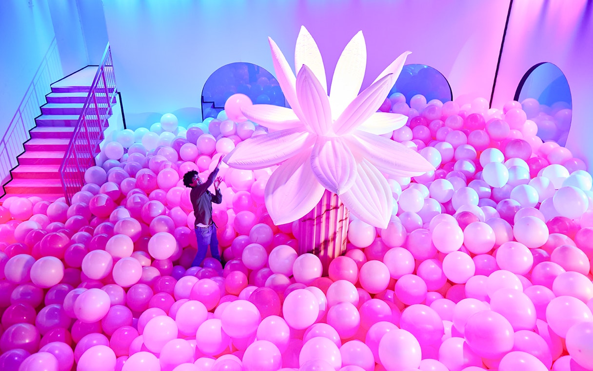 Person exploring pink balloon installation at Bubble Planet, Seattle.